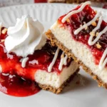 Two slices of Philadelphia cheesecake bars topped with strawberry glaze, drizzled with white chocolate, sprinkled with crushed nuts, and served with a dollop of whipped cream.